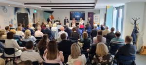 Audience seated for the launch event with a panel discussion taking place at the top of the room.