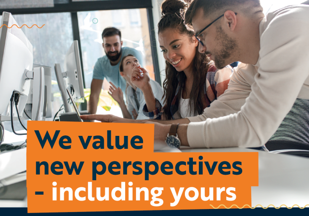 Four employees aged in their twenties sitting at a work station smiling and chatting. One is showing a colleague something on a screen. A caption of "We value new perspectives - including yours" features.